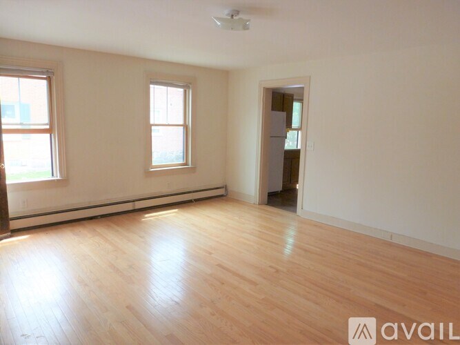 A room with wooden flooring and two windows.
