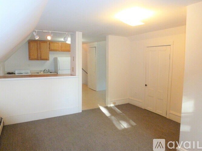 A room with a kitchen area and a carpeted floor.
