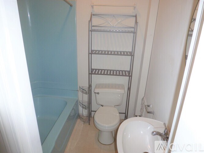 A white toilet sits in a small bathroom with a white sink and a bathtub.