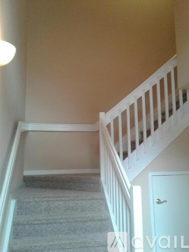 A staircase with a carpeted runner and white balusters.