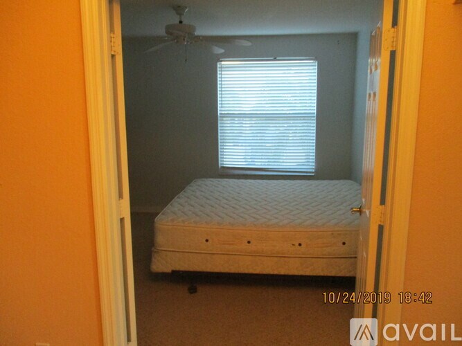 A bedroom with a bed, a ceiling fan, and a window with blinds.