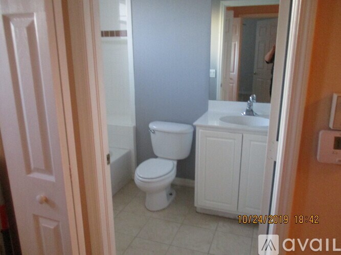 A bathroom with a toilet, sink, and mirror.