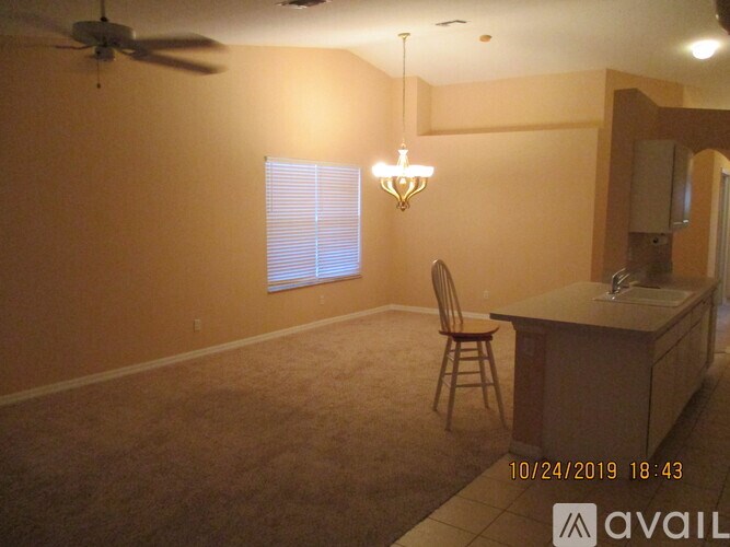 A room with a ceiling fan, a chair, and a table with a cabinet.