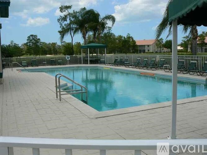 A pool surrounded by a fence and trees.