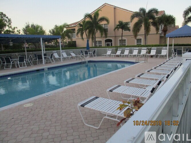 A pool with chairs around it and a building in the background.