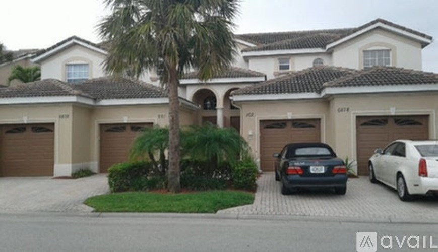 A house with a black car and a white car parked in front.
