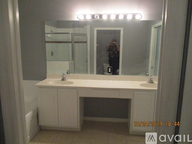 A bathroom with a white vanity and a mirror with lights above it.