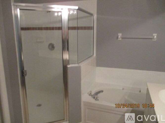 A shower area with a glass door and a white tub.