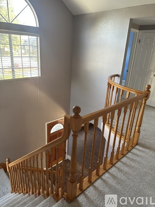 A wooden staircase with a carpeted floor and a door in the background.