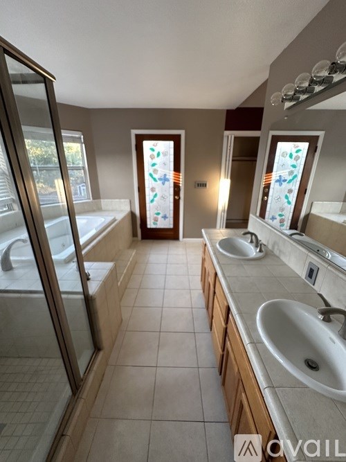 A bathroom with a glass shower door, a bathtub, a sink, and a mirror.