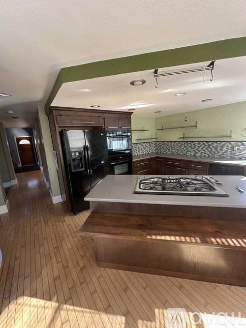 A kitchen with a black fridge and a wooden floor.