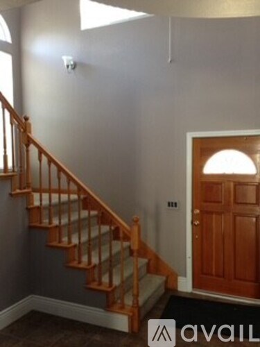 A staircase with a wooden handrail and a door with a wooden frame.