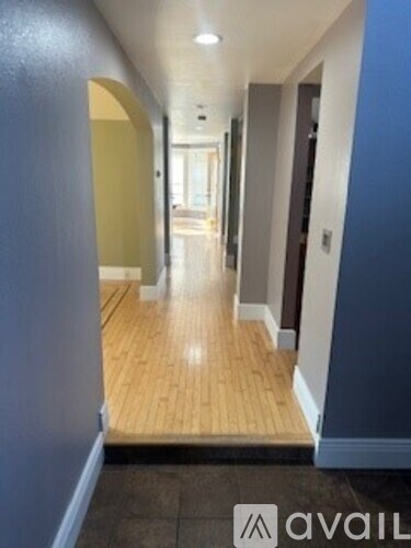 A hallway with wooden floors and blue walls.