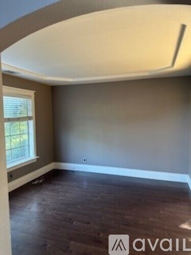 A room with a large window and a wooden floor.