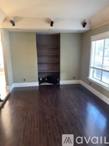 A room with wood flooring and a wall-mounted shelf.