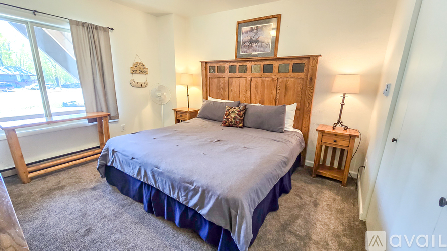 A bedroom with a large bed and a window with a view of trees.