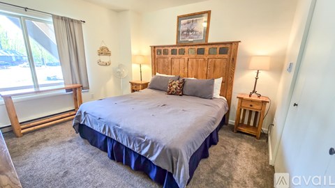 A bedroom with a large bed and a window with a view of trees.