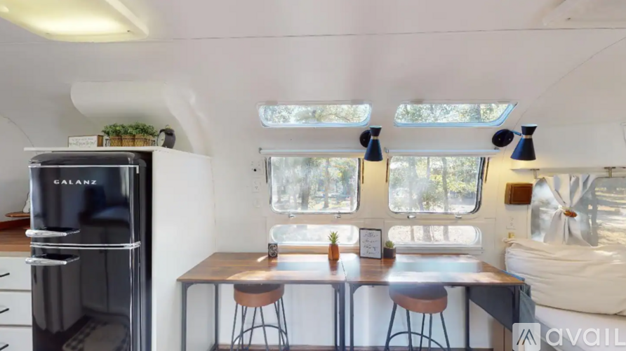A kitchen with a black fridge and a table with four stools.
