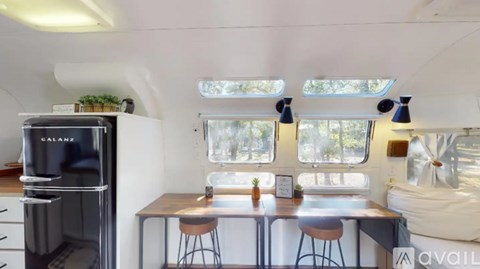 A kitchen with a black fridge and a table with four stools.