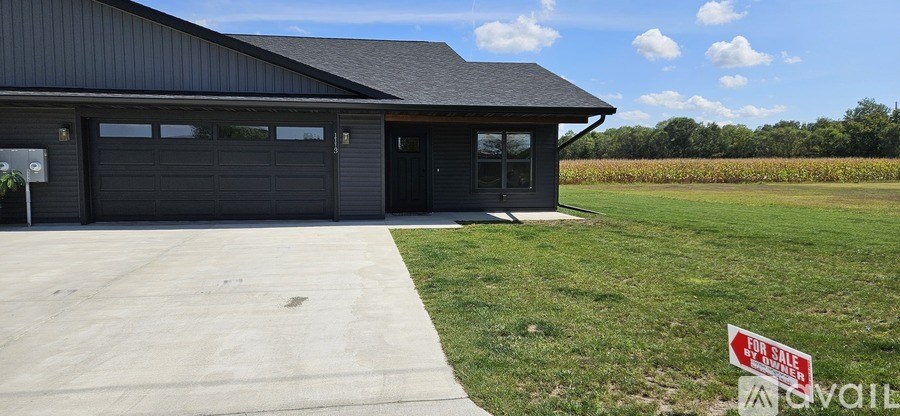 A black building with a sign that says "For Sale" in front of it.