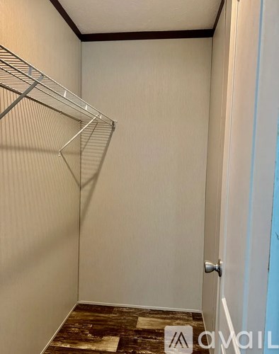 A small, empty room with a white door and a metal rack on the wall.