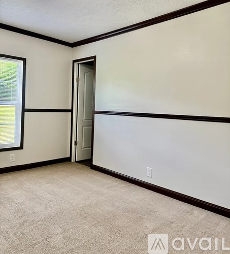 A room with a carpeted floor and a door leading to another room.