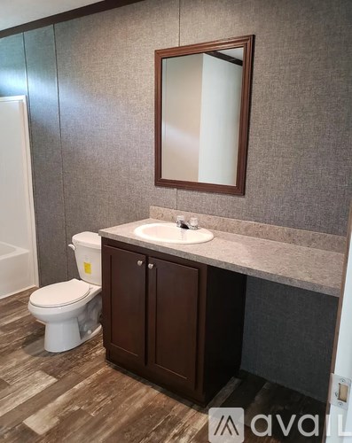 A bathroom with a toilet, sink and mirror.