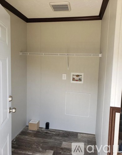 A room with a white wall and a door on the left.