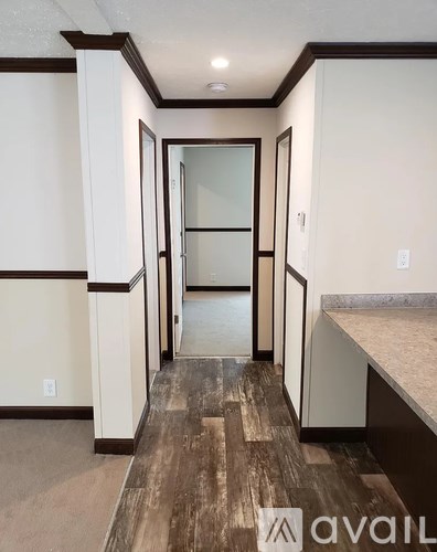 A hallway with wood flooring and white walls.