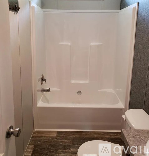 A white bathtub with a shower head and faucet is in a bathroom.