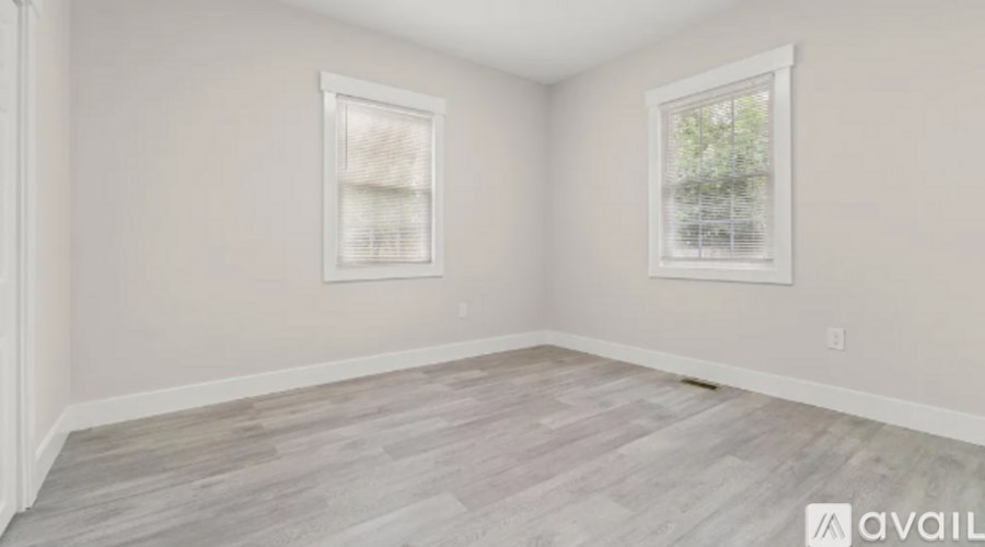 A room with two windows and wooden flooring is available for rent.