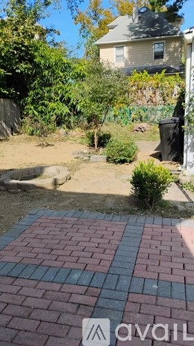 A backyard with a brick patio and a house in the background.