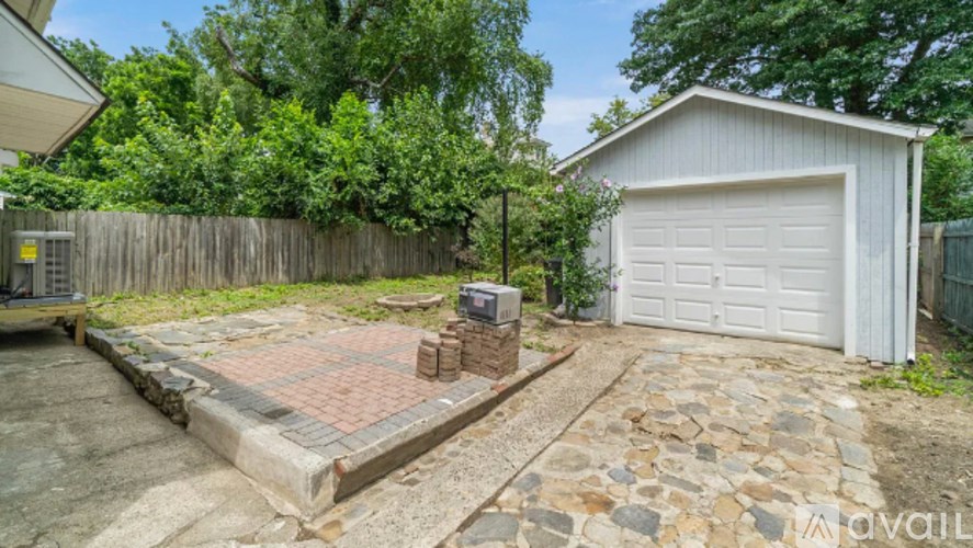 A backyard with a garage and a brick patio.