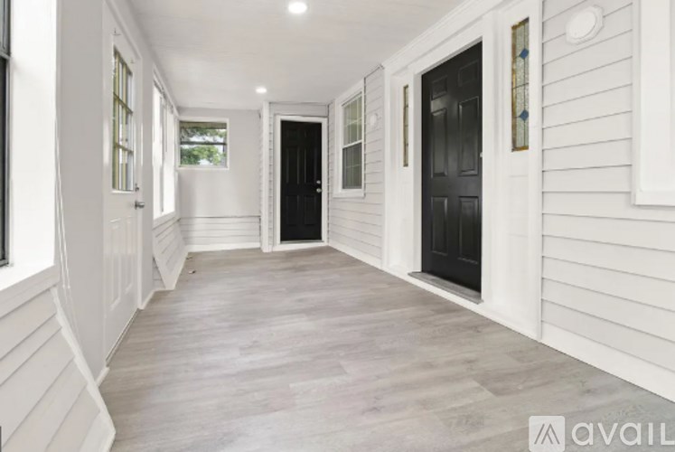 A long hallway with a black door and white walls.