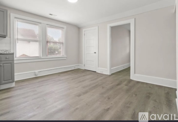 A room with wooden flooring and a window overlooking a house.