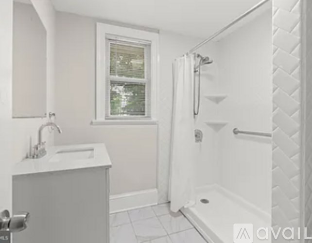 A white bathroom with a window and a shower.