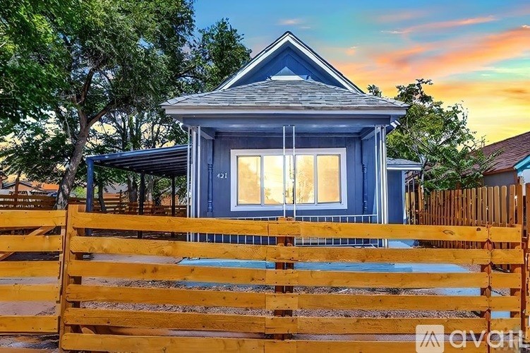 A blue house with a wooden fence in front.
