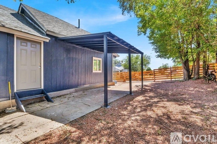 A backyard with a wooden fence and a covered patio area.