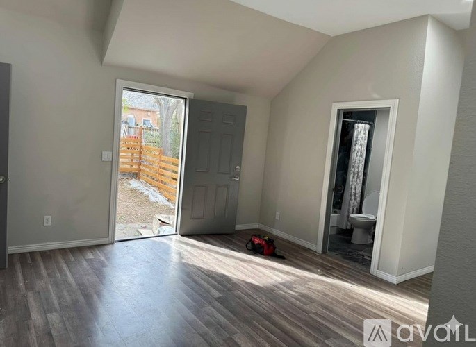 A room with a wooden floor and a sliding glass door leading to a backyard.
