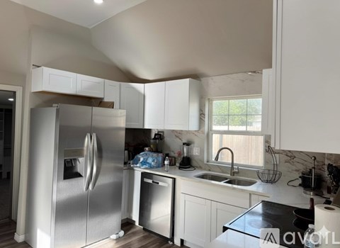 A kitchen with a refrigerator, sink, and cabinets.