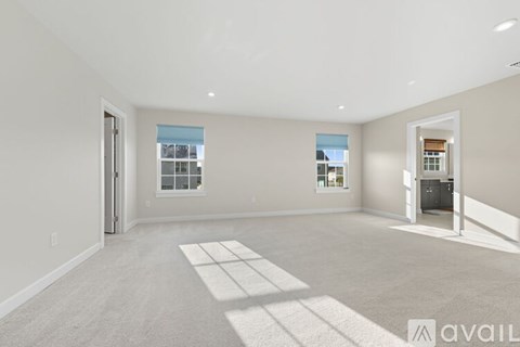 A spacious living room with a large rug in the center and a view of the outside through the window.