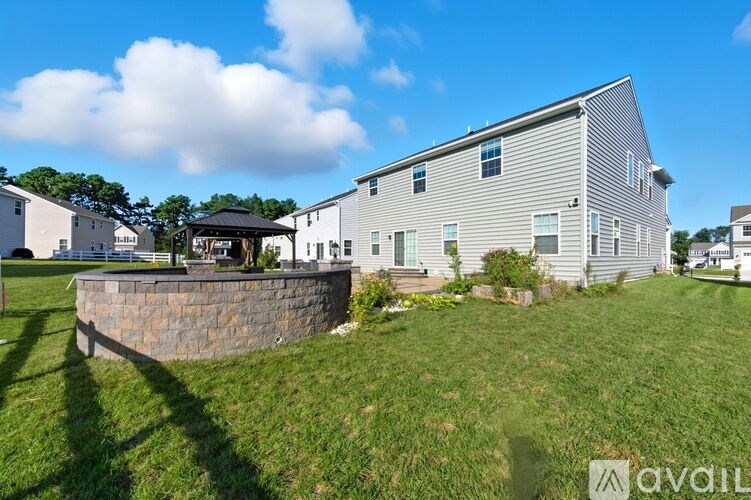 A house with a stone wall in front of it is for sale.