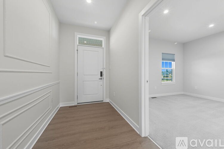 A hallway with a white door and a window in the other room.