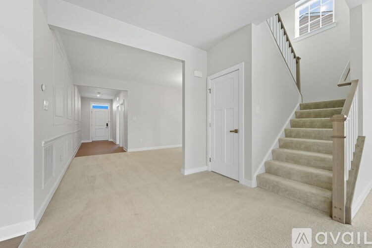 A spacious hallway with a staircase on the right and a door at the end.