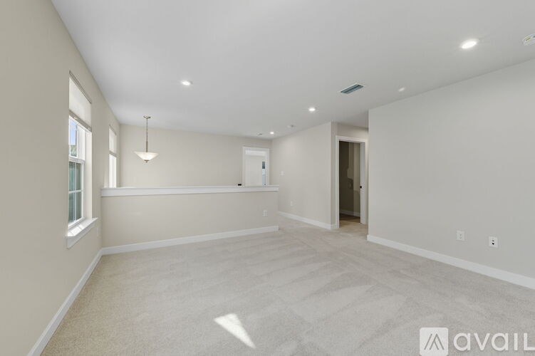 A spacious room with a carpeted floor and a window on the left side.