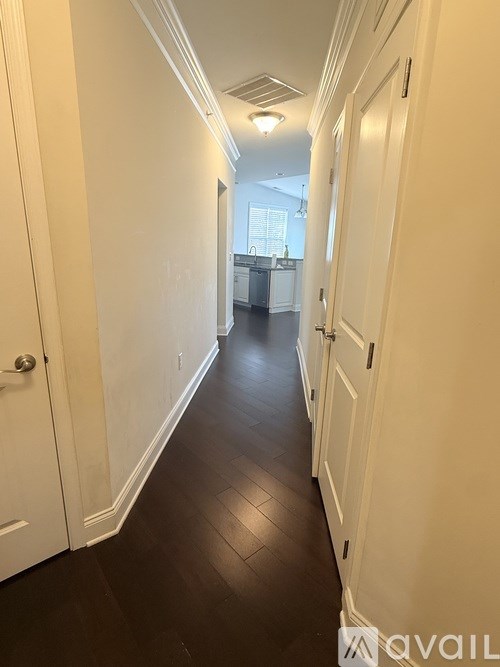 A long hallway with white doors and a kitchen in the distance.