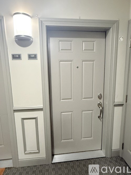 A white door with a silver handle and a wall light above it.