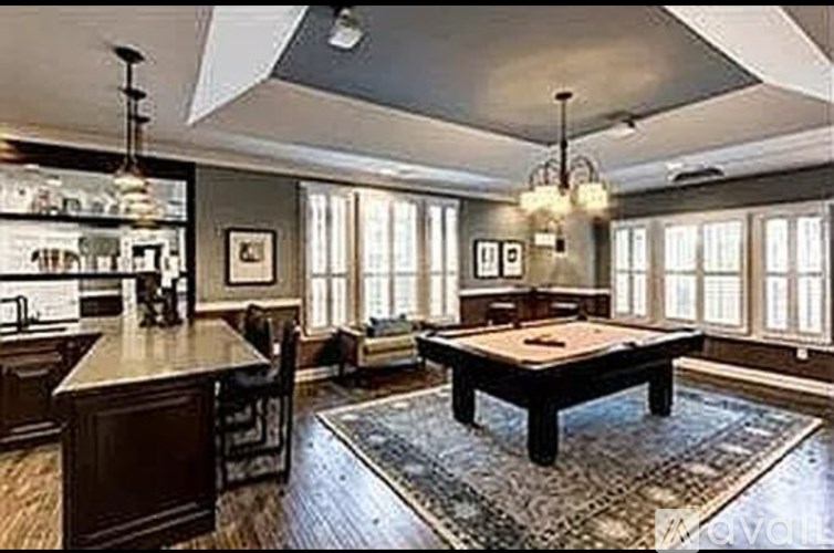 A large, well-lit room with a pool table and a bar area.