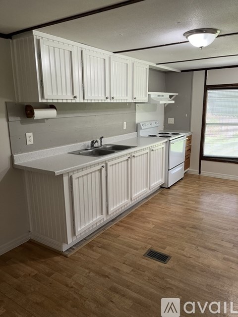 A kitchen with white cabinets and a wooden floor.
