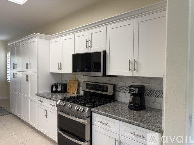 A kitchen with white cabinets and a black stove top oven.